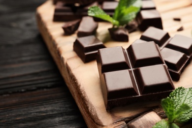 Pieces of dark chocolate with mint on wooden table