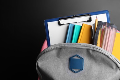 Backpack with different school stationery near blackboard, space for text