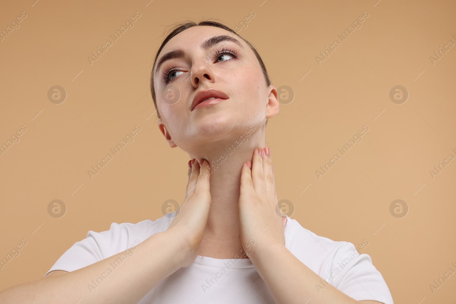 Photo of Beautiful woman touching her neck on beige background