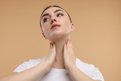 Beautiful woman touching her neck on beige background