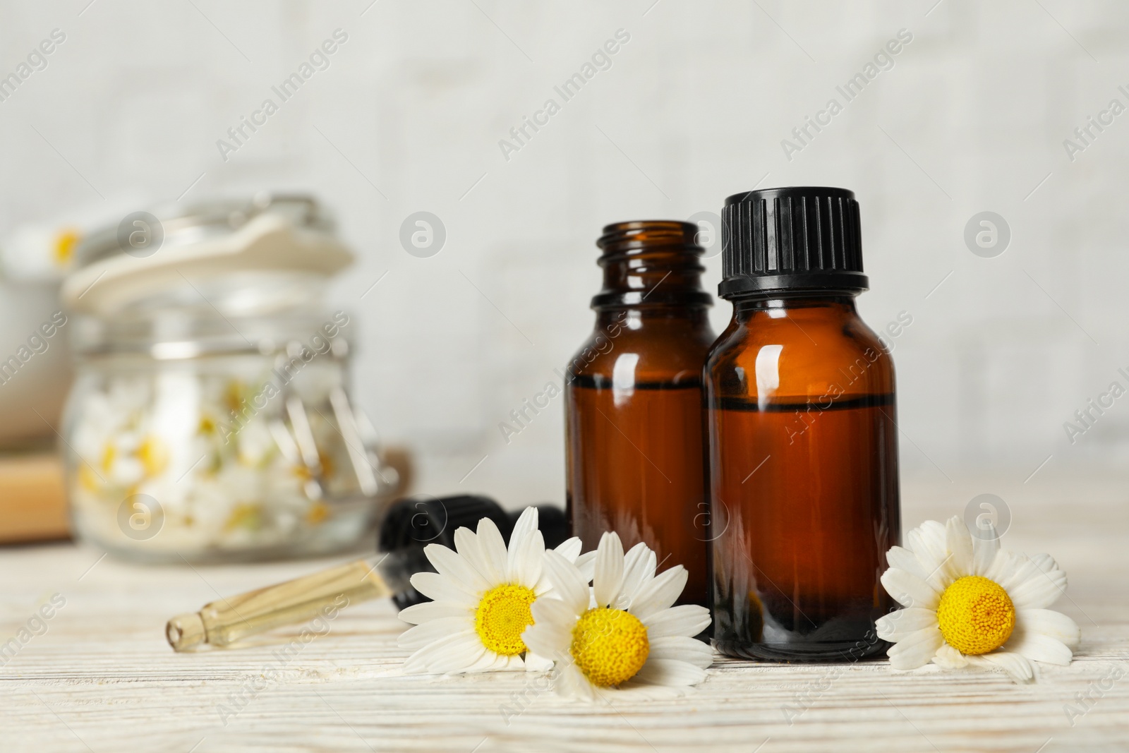 Photo of Composition with bottles of chamomile essential oil on table. Space for text