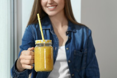 Beautiful young woman with delicious smoothie near window, closeup