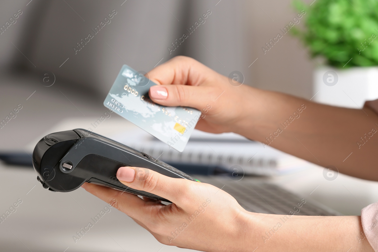 Photo of Woman using modern payment terminal at table indoors, closeup