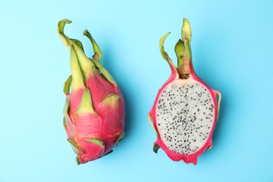 Photo of Delicious ripe dragon fruits (pitahaya) on light blue background, flat lay