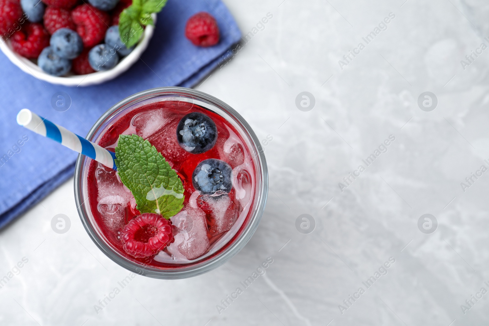 Photo of Delicious berry lemonade made with soda water on grey table, flat lay. Space for text