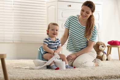 Photo of Mother training her child to sit on baby potty indoors. Space for text
