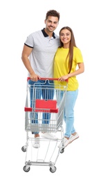 Young couple with empty shopping cart on white background