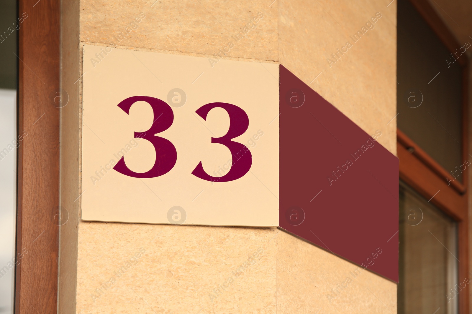 Photo of House number 33 on beige wall outdoors, low angle view