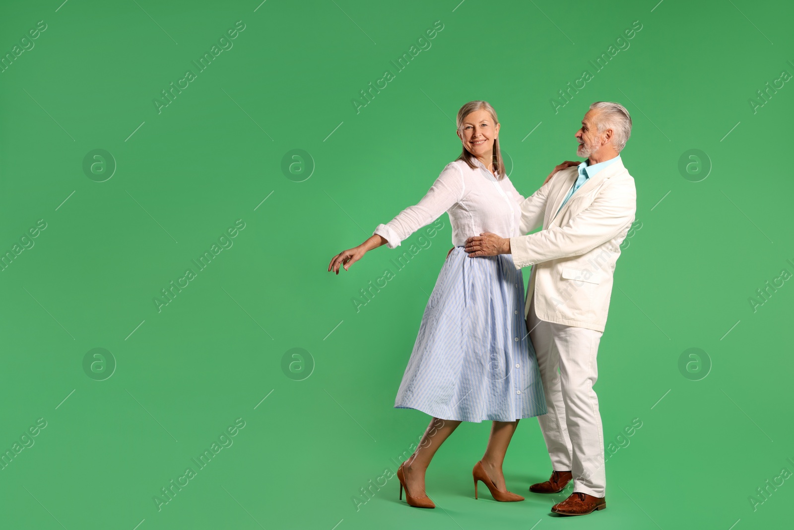 Photo of Senior couple dancing together on green background, space for text