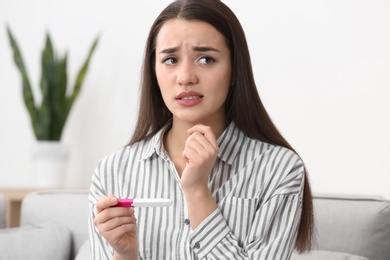 Photo of Young woman with pregnancy test at home. Gynecology and childbirth