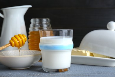 Photo of Glass with milk, honey and butter on grey wooden table