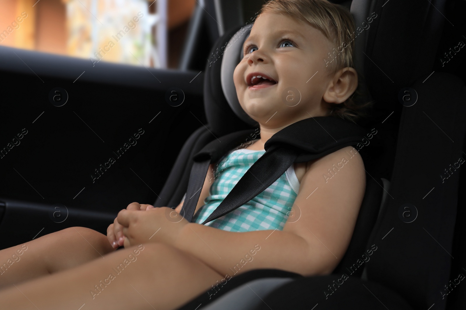 Photo of Cute little girl sitting in child safety seat inside car