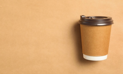Takeaway paper coffee cup on beige background, top view. Space for text