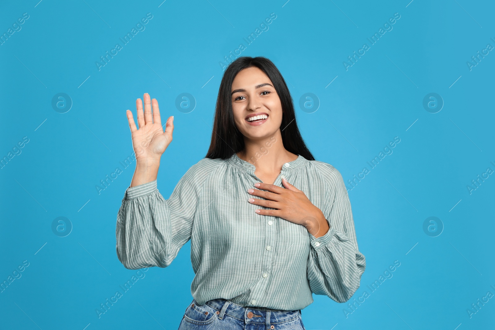 Photo of Happy woman waving to say hello on light blue background