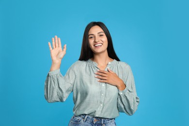 Photo of Happy woman waving to say hello on light blue background