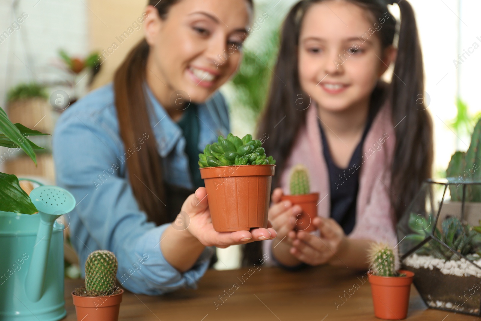 Photo of Mother and daughter taking care of potted plants at home