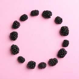 Frame made with fresh blackberries on pink background, top view. Space for text