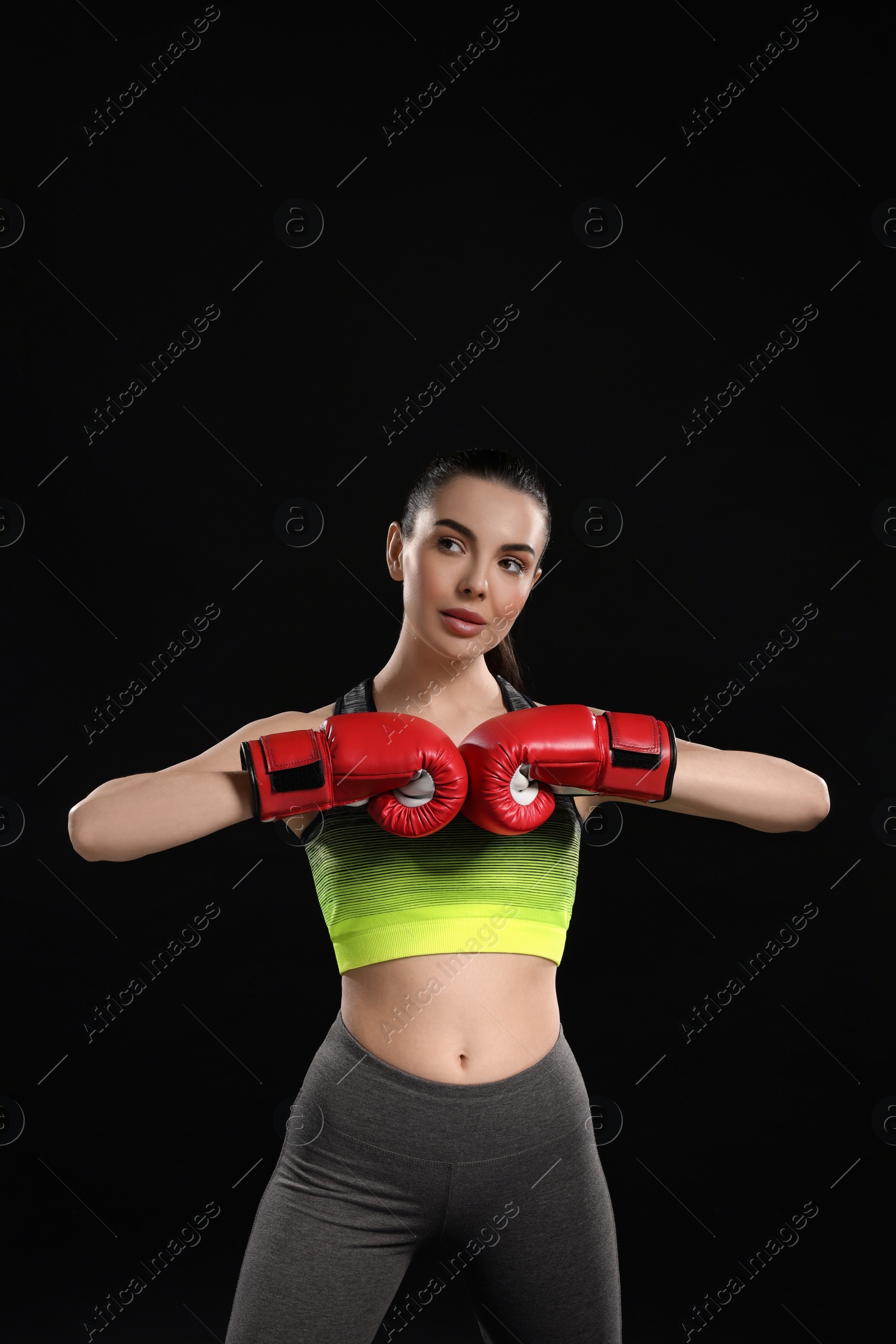 Photo of Portrait of beautiful woman in boxing gloves on black background