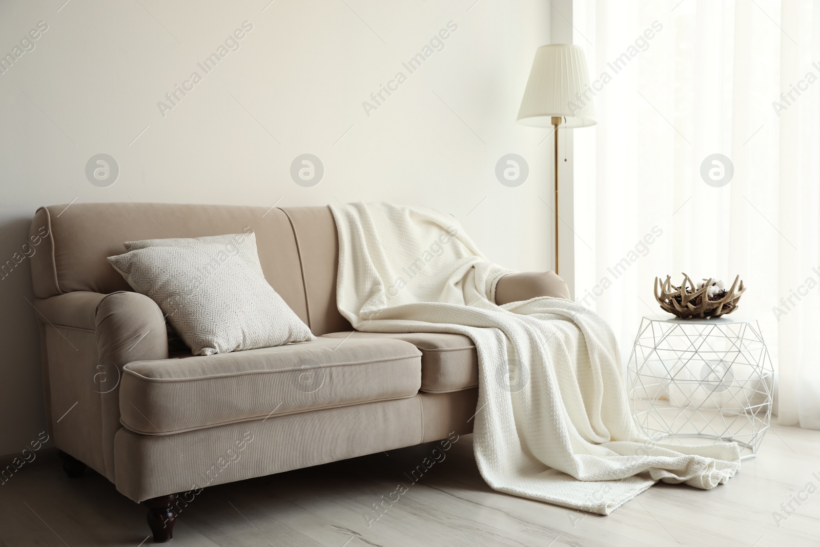 Photo of Comfortable sofa with cushions and plaid in stylish living room interior