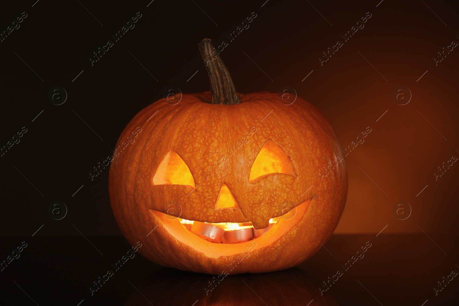 Photo of Halloween pumpkin head. Glowing jack lantern on dark background