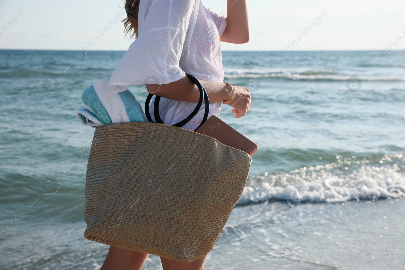 Photo of Woman carrying bag with beach towel near sea, closeup