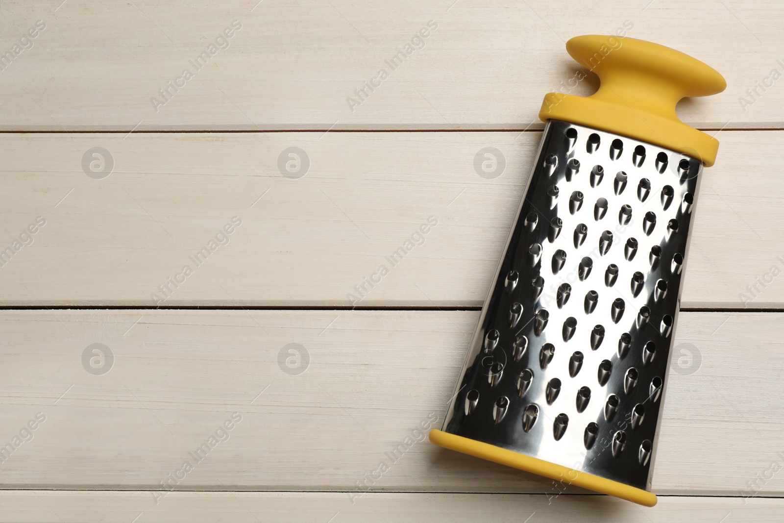 Photo of Modern grater on white wooden table, top view. Space for text