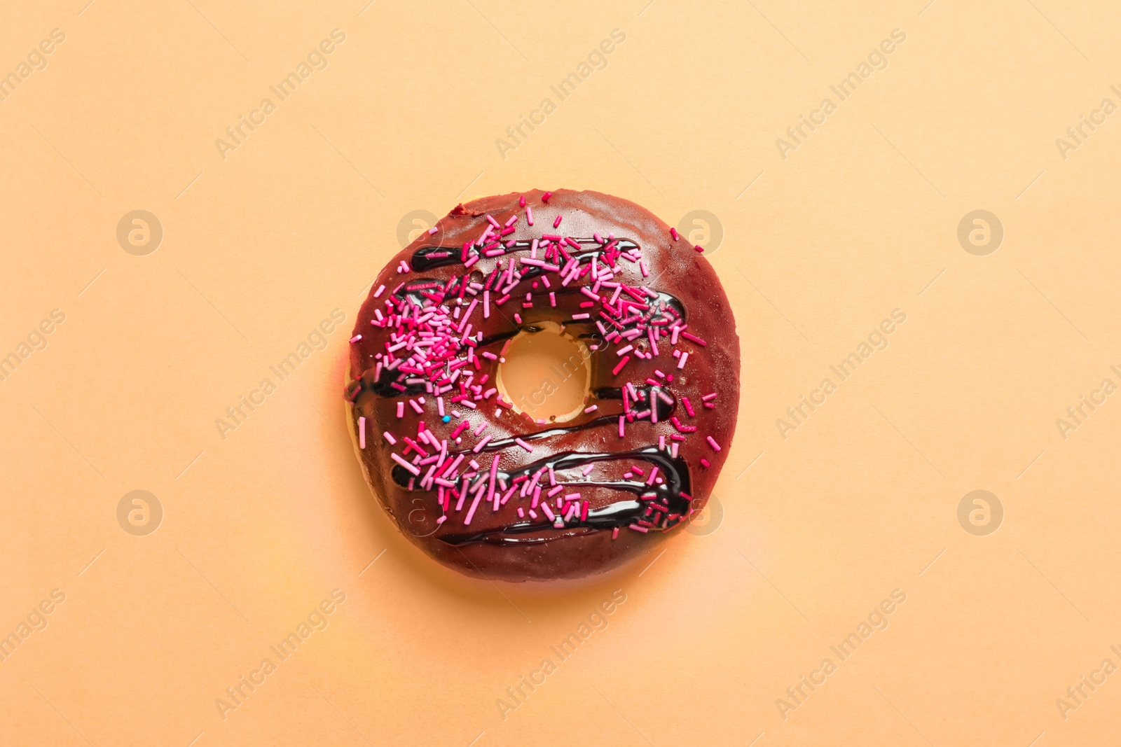 Photo of Delicious glazed doughnut with sprinkles on color background, top view