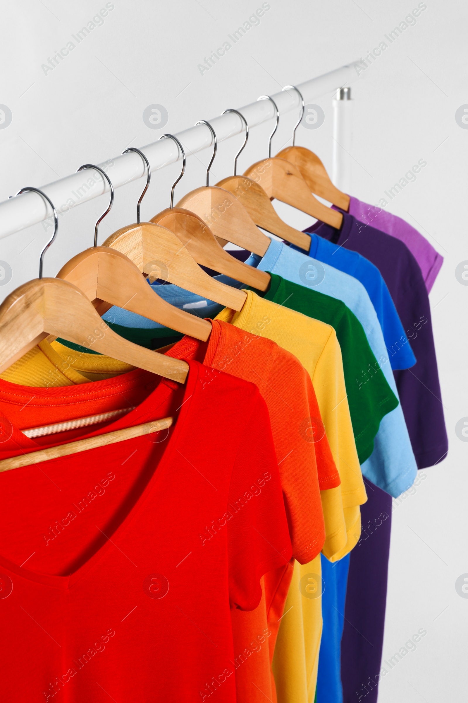 Photo of Colorful clothes on hangers against white background