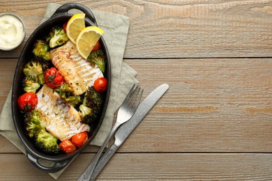 Photo of Tasty cod cooked with vegetables served on wooden table, flat lay. Space for text