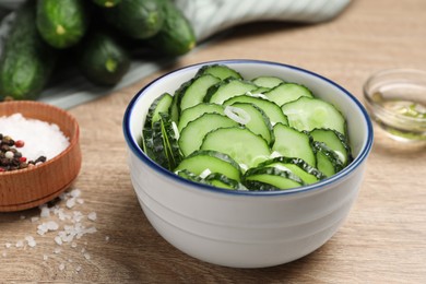 Photo of Delicious salad with cucumbers and green onion in bowl on wooden table