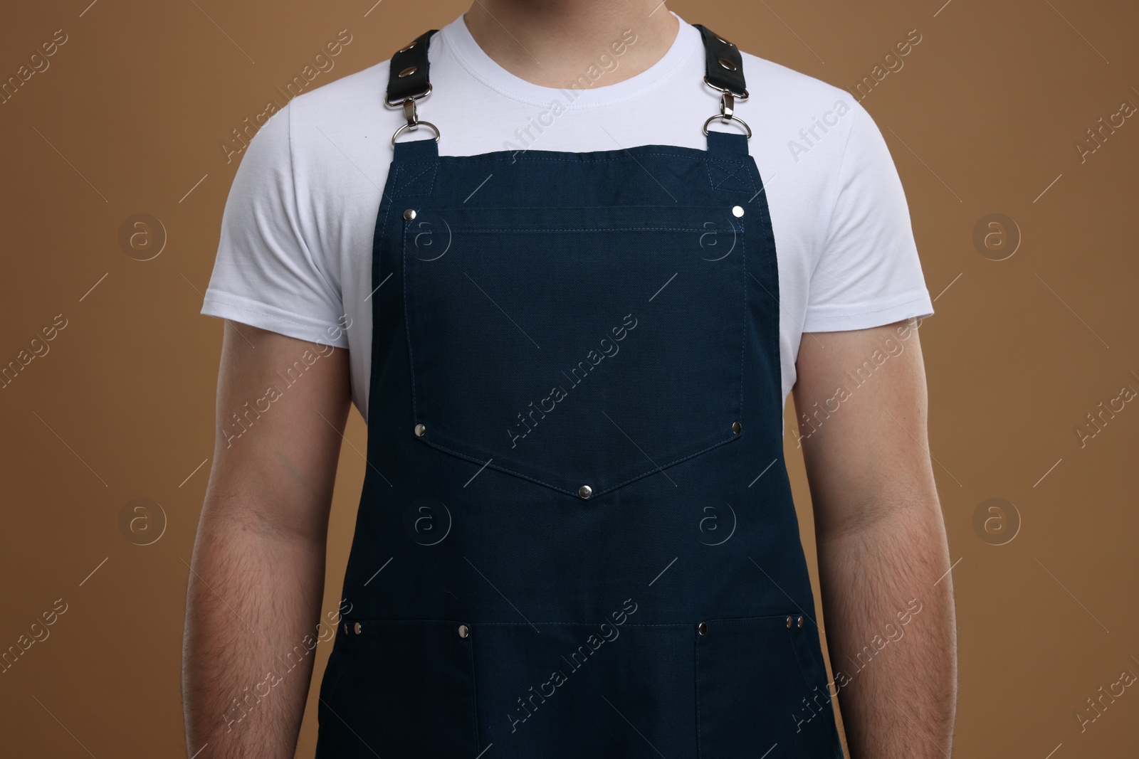 Photo of Man in kitchen apron on brown background, closeup. Mockup for design