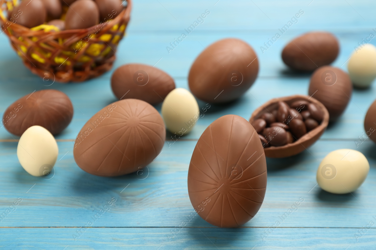 Photo of Sweet chocolate eggs on light blue wooden table