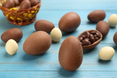 Sweet chocolate eggs on light blue wooden table