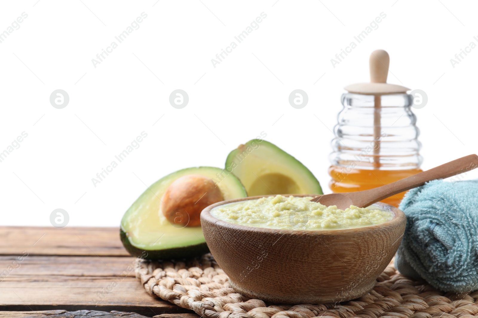 Photo of Homemade hair mask in bowl, fresh ingredients and towel on wooden table against white background. Space for text