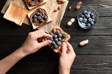 Photo of Woman holding toast bread with blueberries over table