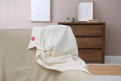 Men's shirt with lipstick kiss mark on sofa indoors