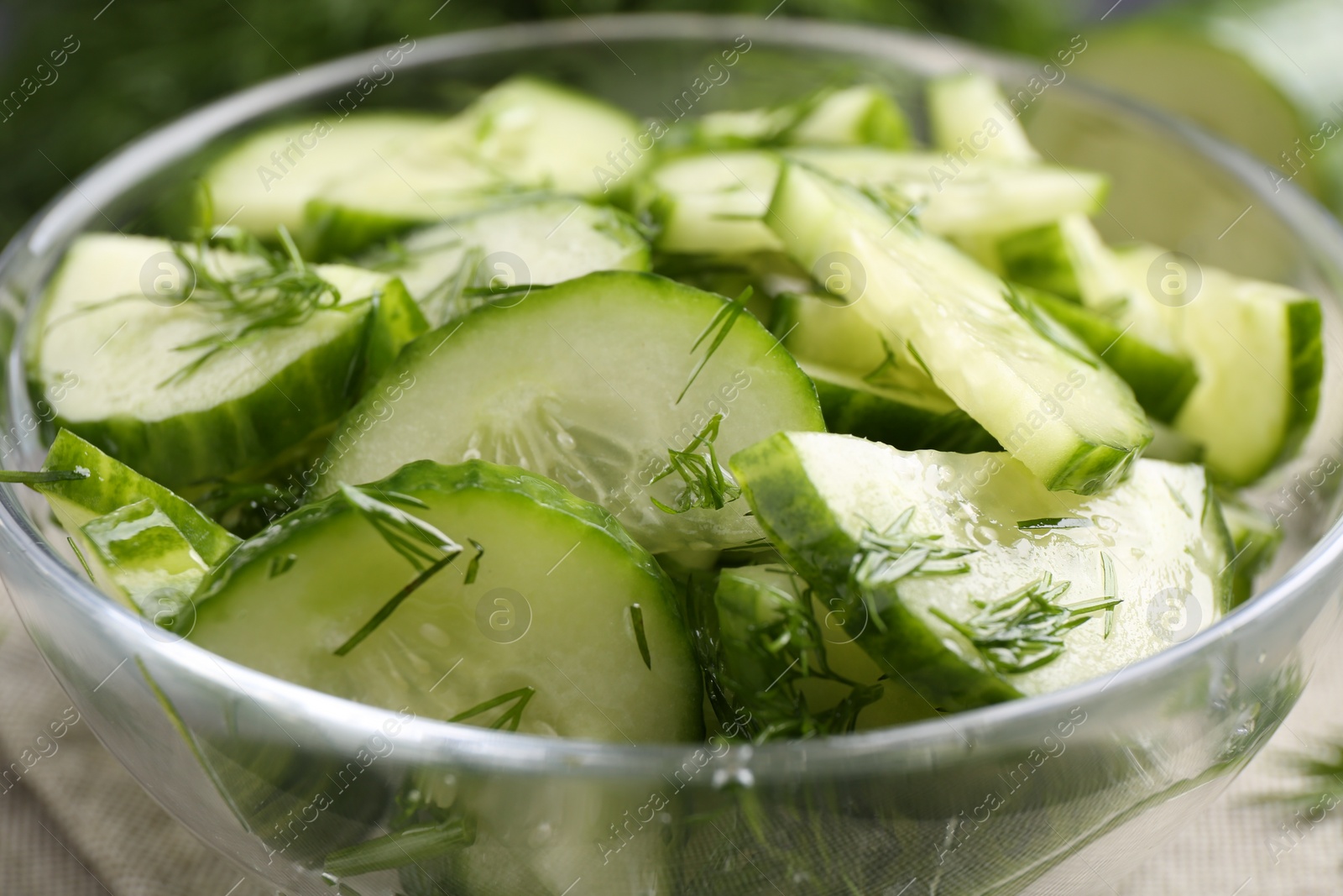 Photo of Cut cucumber with dill in glass bowl, closeup