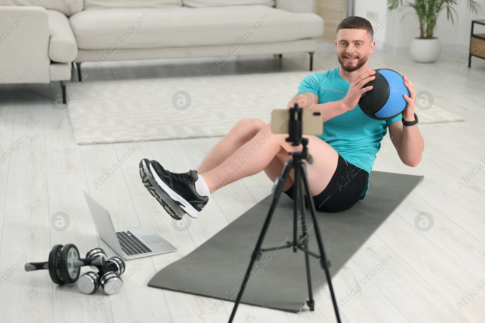 Photo of Trainer with ball streaming online workout on phone at home