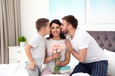 Father and son congratulating mom in bedroom. Happy Mother's Day