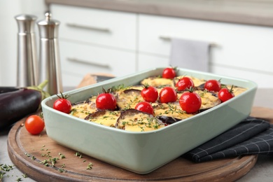 Photo of Baked eggplant with tomatoes and cheese in dishware on table against blurred background