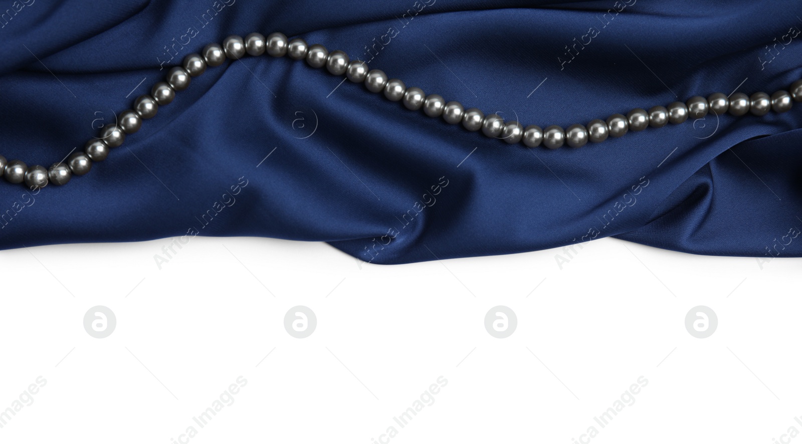 Photo of Beautiful pearls and dark blue silk on white background