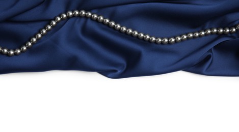 Photo of Beautiful pearls and dark blue silk on white background