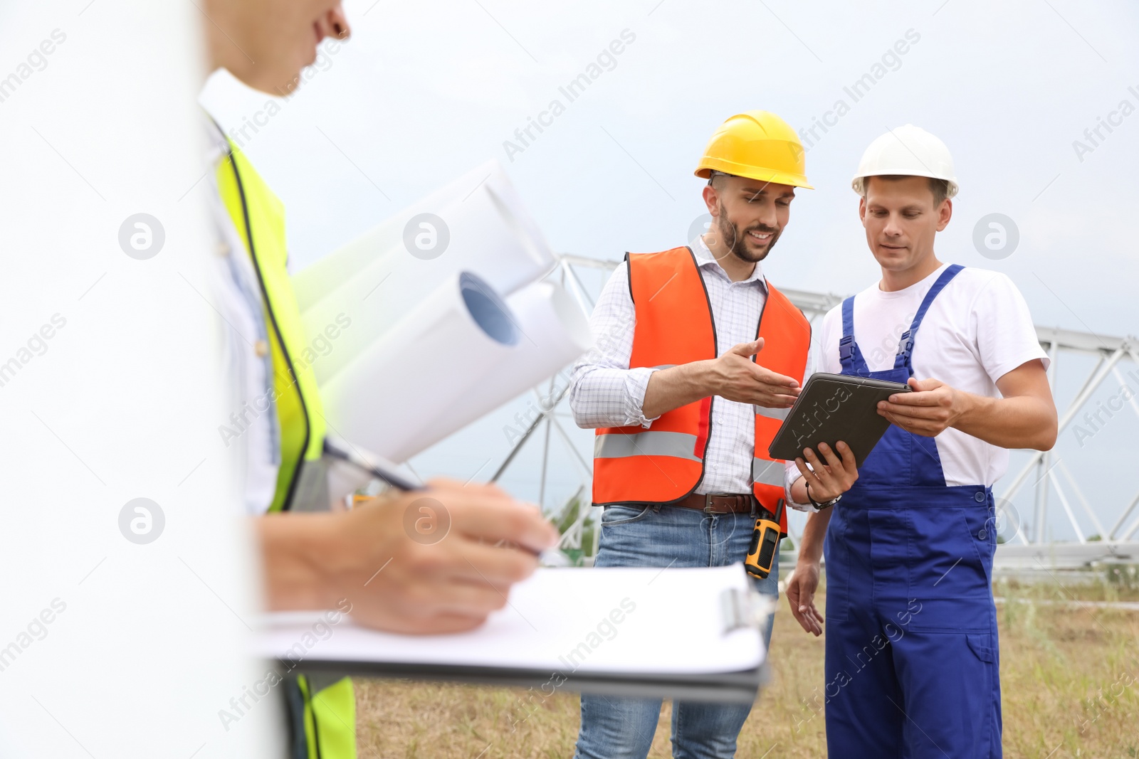 Photo of Professional engineers working on installation of electrical substation outdoors