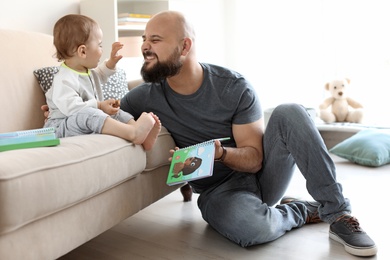 Dad reading book with his little son in living room