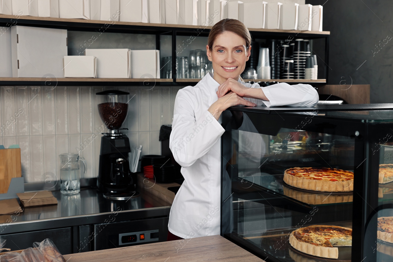 Photo of Professional baker near showcase with pastries in store