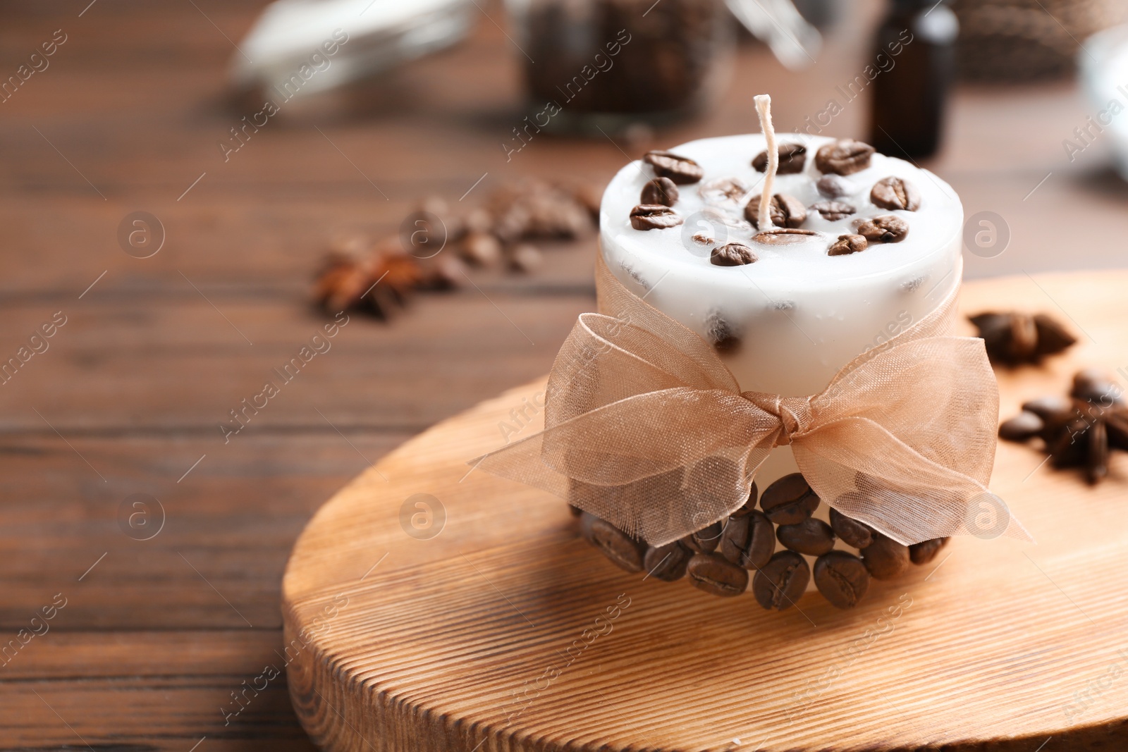 Photo of Board with coffee candle and beans on wooden table. Space for text