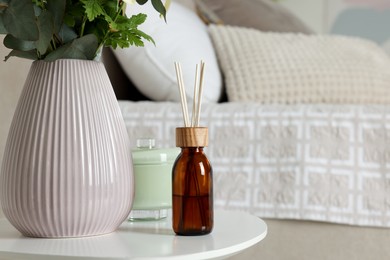 Photo of Aromatic reed air freshener on white table in bedroom. Space for text