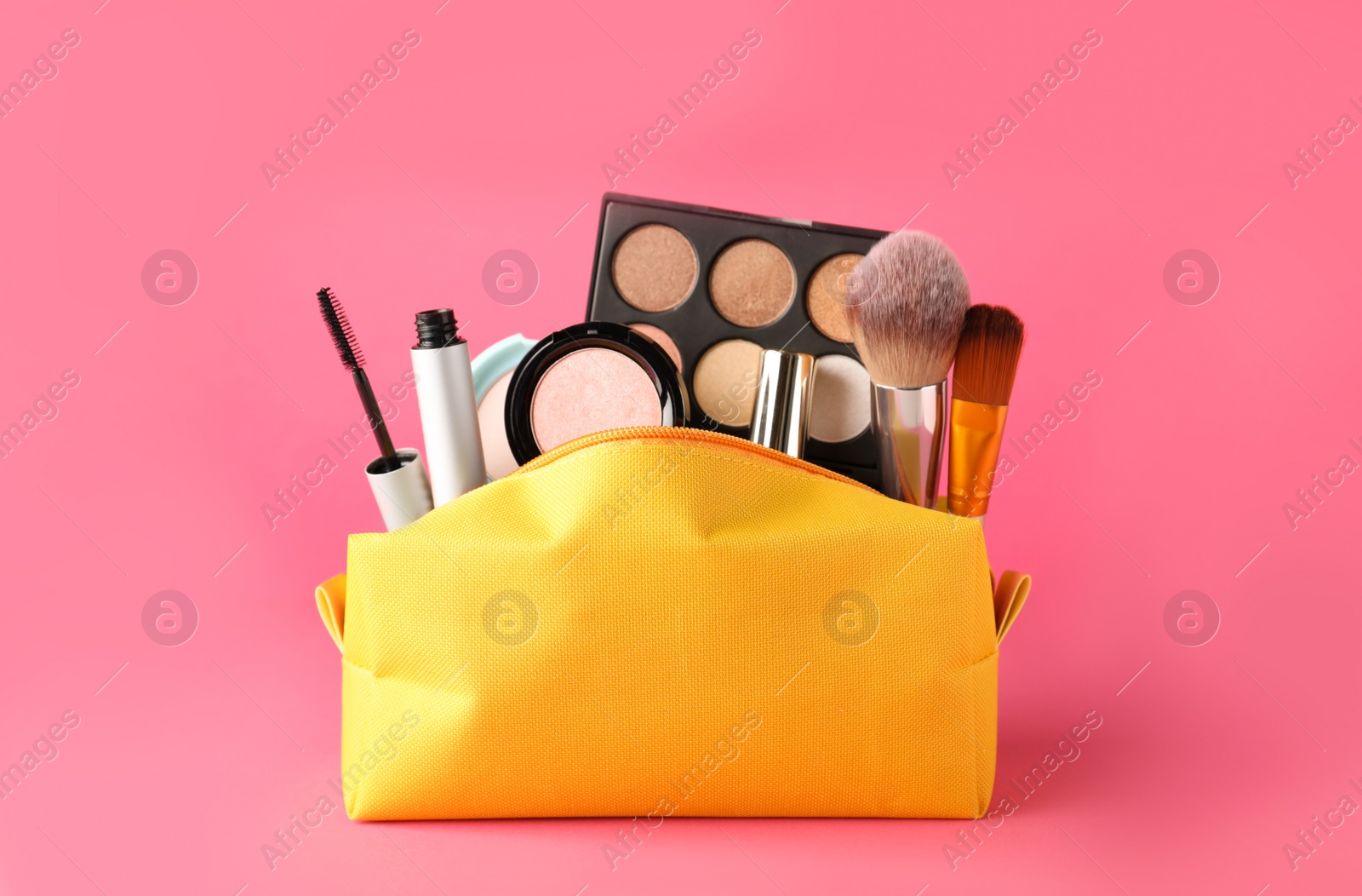 Photo of Cosmetic bag with makeup products and accessories on pink background