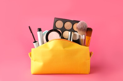 Cosmetic bag with makeup products and accessories on pink background