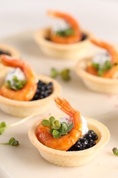 Delicious canapes with shrimps and black caviar on light table, closeup